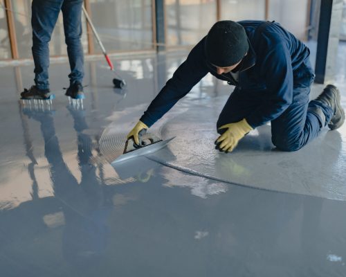 The worker applies gray epoxy resin to the new floor